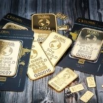 Verschiedene Goldbarren und -münzen auf einem Holzuntergrund.